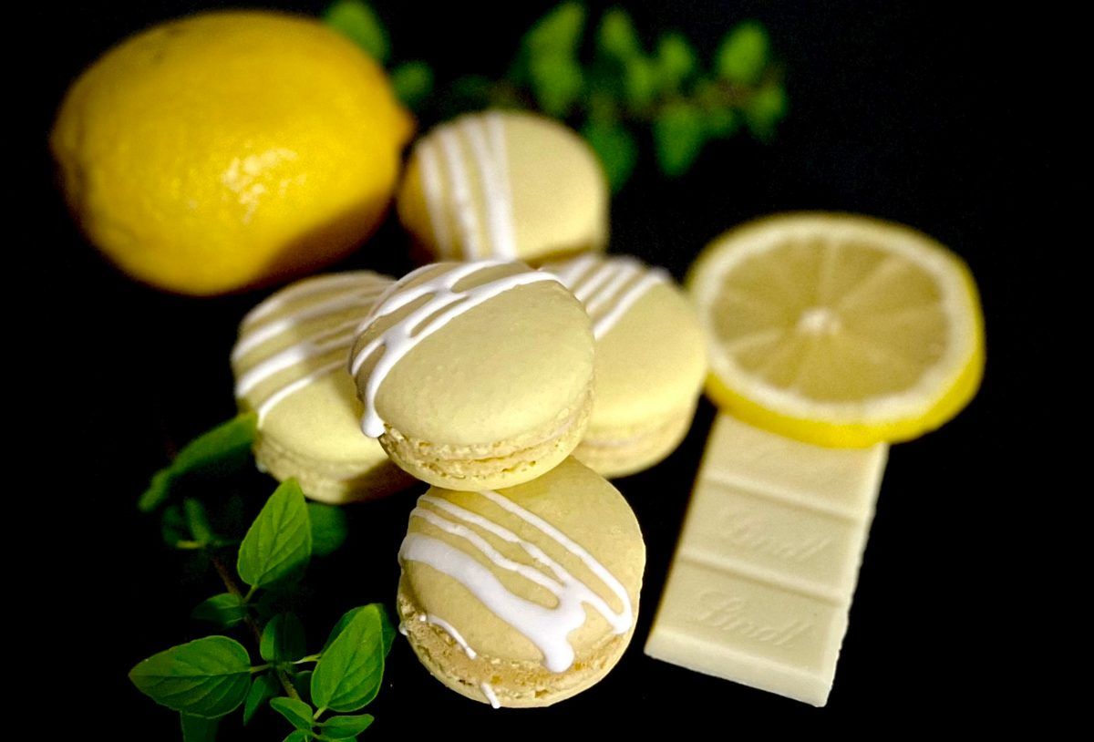 Pale yellow lemon macarons with white drizzle, fresh lemon, mint, and white chocolate