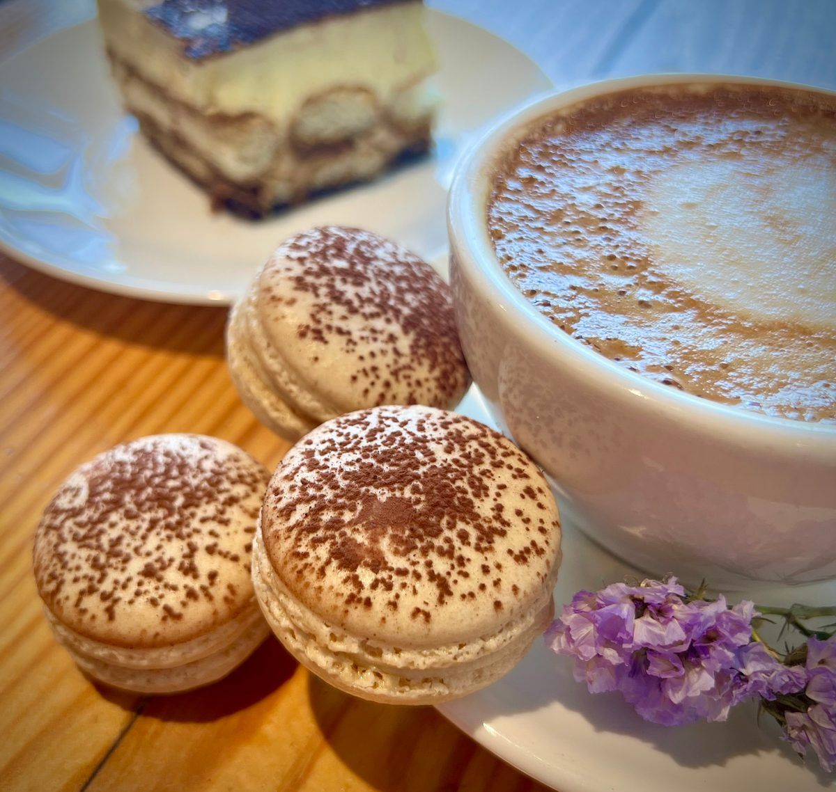 Cocoa-dusted tiramisu macarons served with coffee and a slice of tiramisu